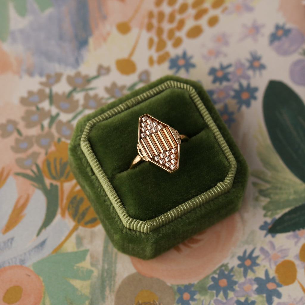A geometric diamond-shaped bezel surrounds a beaded focal